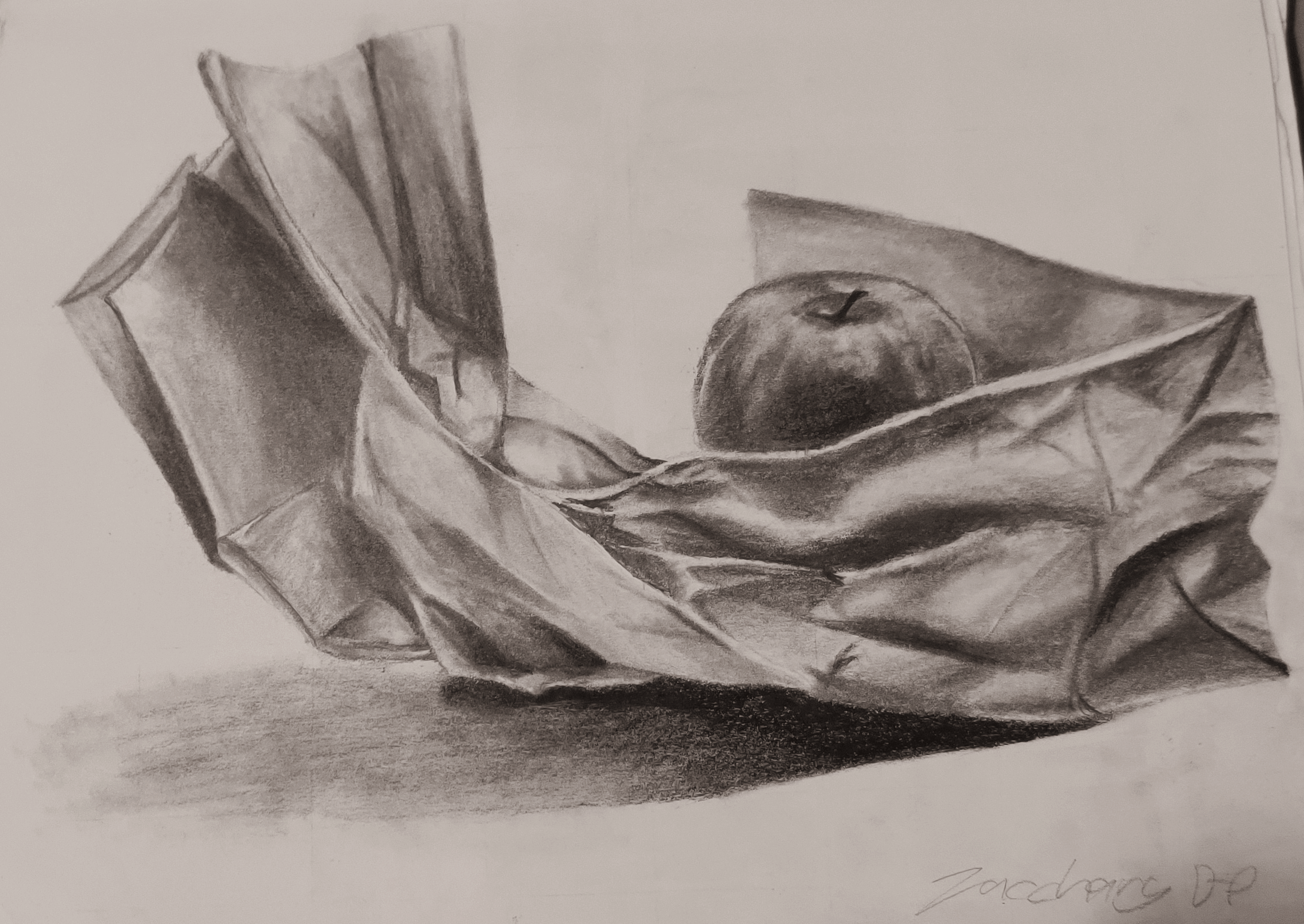 A value drawing of an apple resting on a paper bag.